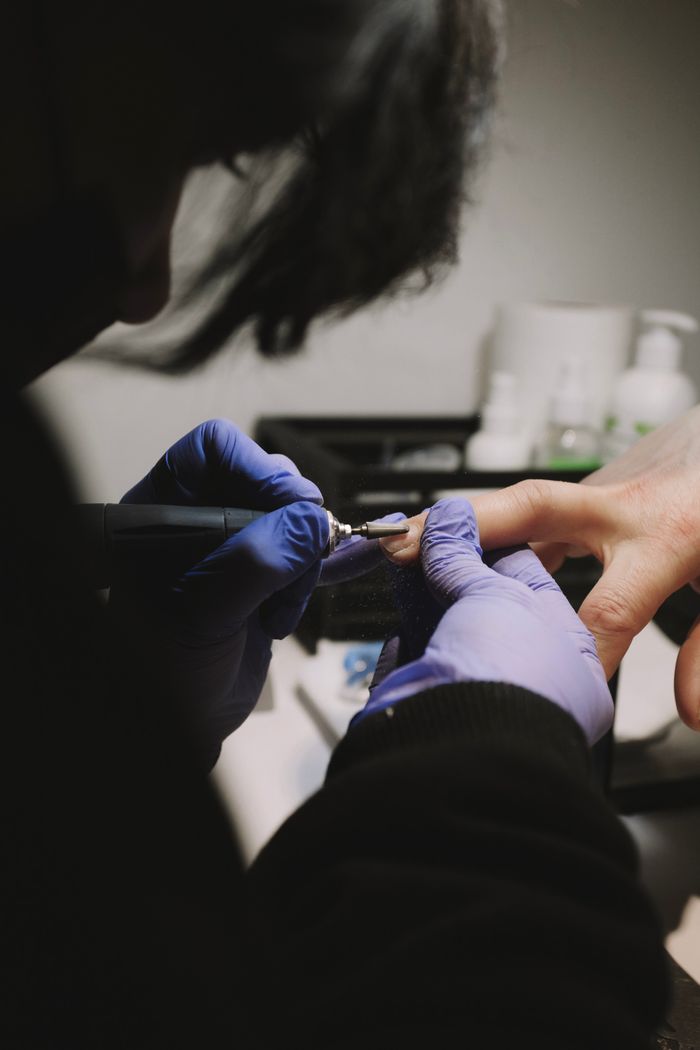 A beautician provides professional manicure services in a New Delhi salon, focusing on detailed nail care.