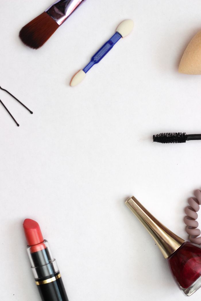 Top view of beauty essentials scattered on a white surface, showcasing lipsticks and brushes.