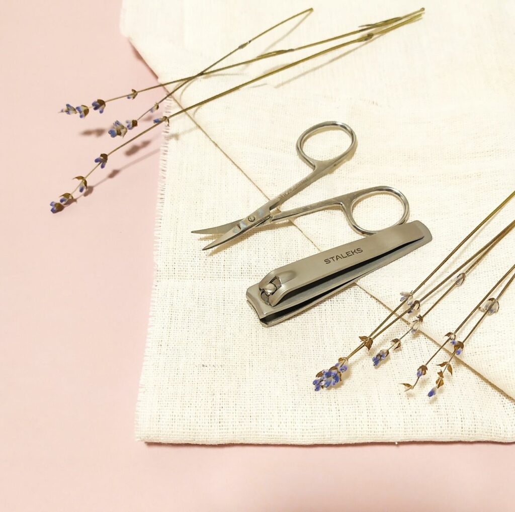 Aesthetic arrangement of nail care tools with lavender on a textured fabric background for a serene look.