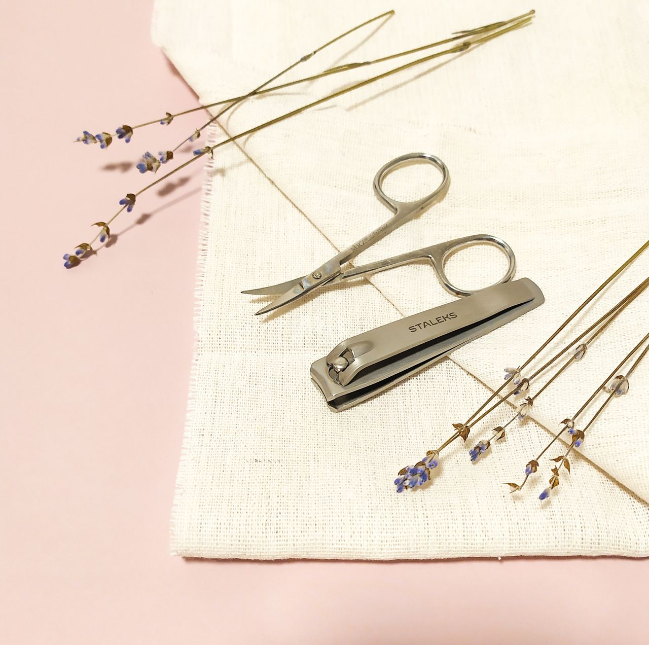 Aesthetic arrangement of nail care tools with lavender on a textured fabric background for a serene look.